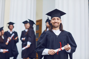 Male graduate is smiling against the background of university graduates.