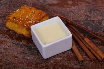Condenced milk in the bowl with sinnamon and pastry