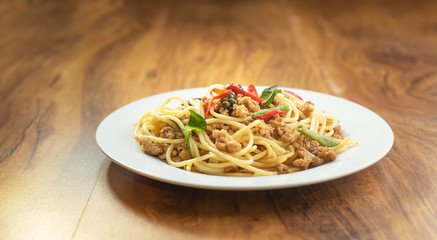 Spaghetti Stir Fried With Spicy Pork in the dish on the wooden table, top view