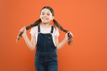 Wellbeing and health. Childhood concept. Fashion girl. Girl adorable kid stand over orange...