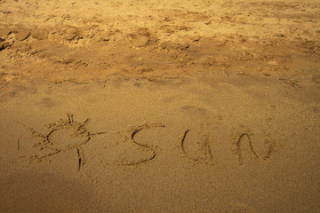 Sun written in the sand oh the beach
