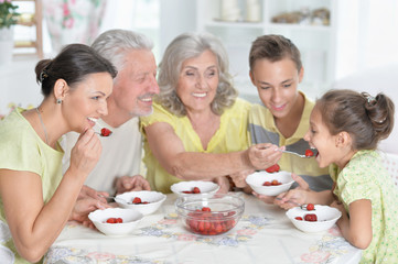 Portrait of big happy family eating fresh strawberries at kitchen