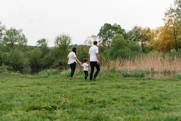 Happy family: mother father and child son on nature on sunset. Mom, Dad and kid laughing and hugging, enjoying nature outside. Sunny day, good mood. concept of a happy family