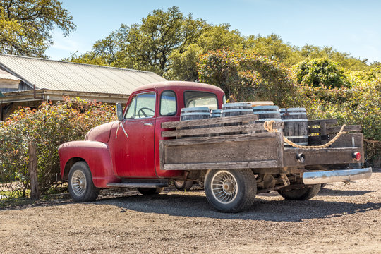 Red, old pickup truck and wine barrels