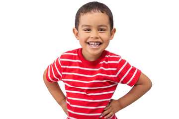 A mixed race young boy laughs while looking at the camera. The toddler wears a red white striped shirt as he smiles at the camera with hands on his hips.