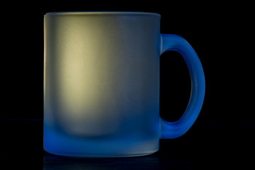 Glass mug on black background  with yellow and blue lighting
