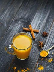 Turmeric tea in a Cup of cinnamon on a wooden dark background