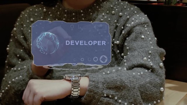 Unrecognizable woman working with HUD hologram of a smart watch with text Developer. Female hands with future holographic technology in wrist watches