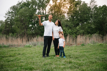 Fototapeta premium Happy family: mother father and child son on nature on sunset. Mom, Dad and kid laughing and hugging, enjoying nature outside. Sunny day, good mood. concept of a happy family