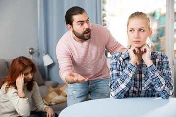 Sad young girl having conflict with boyfriend in home interior
