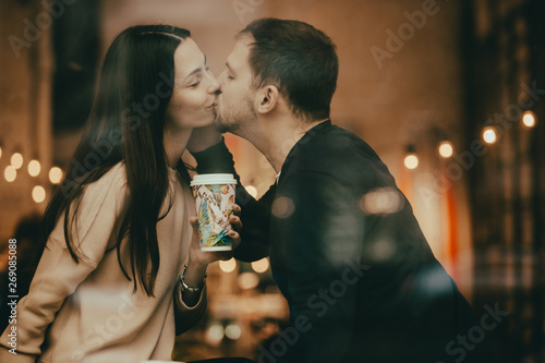 Happy Lovers Guy And Girl Are Kissing On The Windowsill In A Cafe