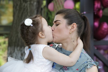 Fototapeta premium baby in a pink dress kisses her mother for her three year birthday