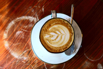 Coffee cup with cappuccino on the worn polished tabletop top view