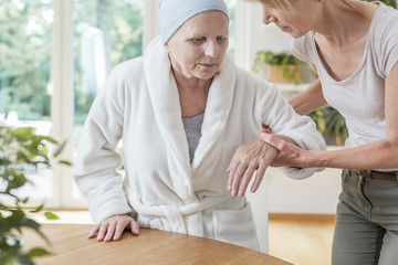 Daughter helping her ill and weak mother. Cancer home treatment concept