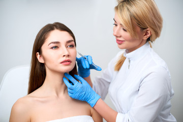 Beautician doctor with botulinum toxin syringe making injection to to remove crow's feet. Cheek...