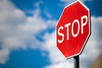 STOP traffic sign on a background of blue sky with white clouds.