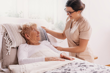 Elderly woman in hospital bed with social worker helping her