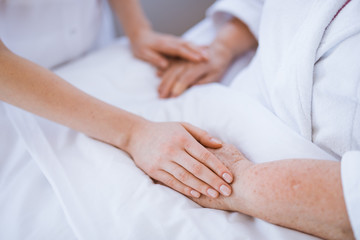 Fototapeta na wymiar Closeup of young woman holding senior's woman hands