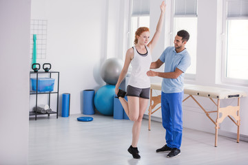Sportswoman exercising while personal trainer helping her during physical workout