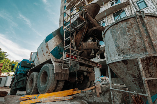 Concrete mixer pours liquid cement into an iron container at construction site