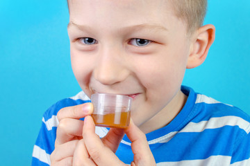 boy takes multi vitamin syrup on blue background