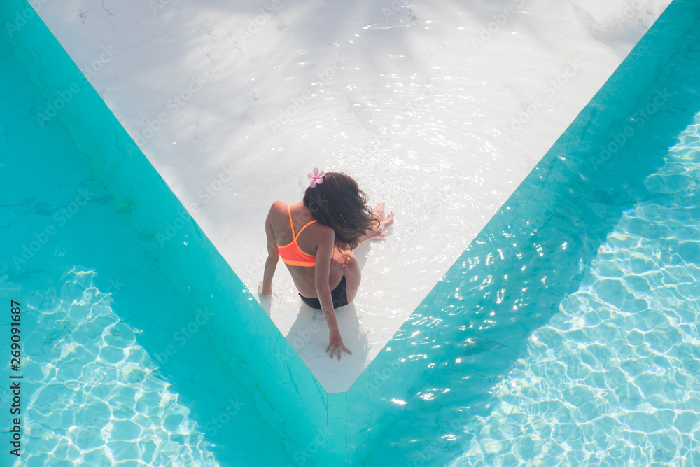 Wall mural Top view aerial photo of model in bright swimwear relaxing in hotel pool during her summer weekend