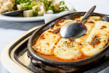 Baked cheese with paprika in a clay pot on the table, traditional serbian food