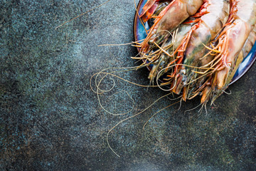 Giant Raw fresh Tiger Prawns in the plate over stone background, top view