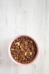 Homemade chocolate granola with nuts in a pink bowl, top view. From above, overhead, flat lay. Space for text.