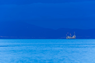 Offshore oil rig at dusk, with continent in the background