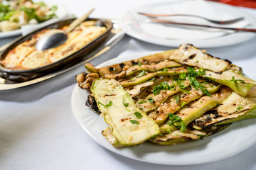 Close up on zucchini courgette Summer squash salad with garlic and oil on a white plate on the table