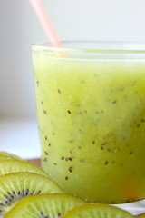 Fototapeta na wymiar Kiwi smoothies in a glass next to fresh kiwi slices on a blue wooden table. fruit drink.copy space