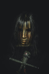 Creepy witch girl with voodoo doll on black background