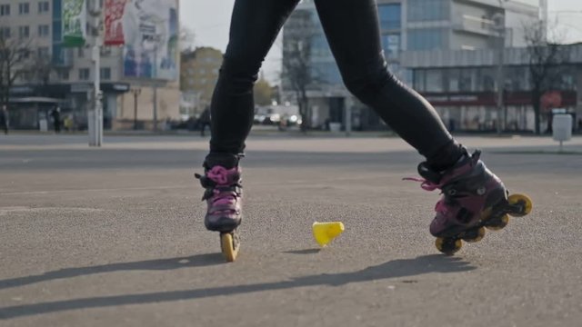 Close up of young woman goes rollerblading. Outdoor activities in summer. Woman rides on roller skates and whirl