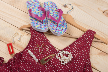 Fashion trends - flip flops, red dress in polka dots on hanger and jewelry: pearl necklace, hair pearl clip, earrings