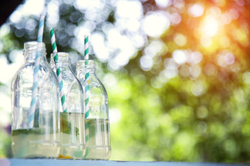 Bottles of fresh lemonade on the background of natural bokeh.