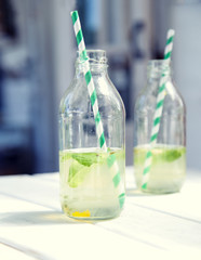 Two bottles of fresh lemonade on a wooden table.