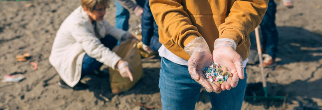 Detail of young man hands showing microplastics on the beach
