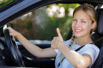 Fototapeta na wymiar beautiful smiling girl in car with thumbs up signal