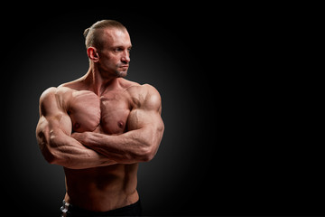 Sport concept. Fitness athlete with perfect muscles poses on camera over black background.