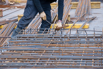 Hands of construction worker. Worker mounts steel bars for reinforcement of concrete or cement