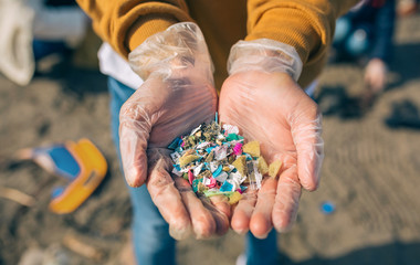Detail of hands showing microplastics on the beach - obrazy, fototapety, plakaty