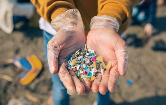 Detail of hands showing microplastics on the beach