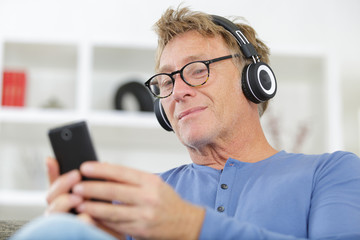 mature man using smartphone while listening to music