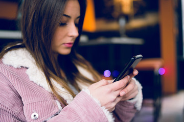 Young woman teenage using mobile phone to text message at the cafe browsing internet