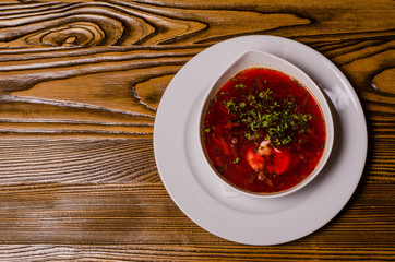 Beats soup, borsch with sour cream; bead and pickles on a background. borsch in a white dish, slices of bread on a wooden cutting board, whole pickles in a wooden dish.