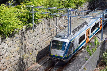 The train moves, goes by rail. Railroad tracks against the background of a stone wall.
