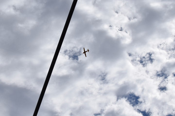 Airplane in the cloudy sky. High voltage cable against the sky and cloud.