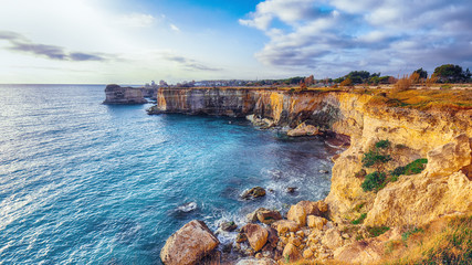 Fototapeta na wymiar Picturesque seascape with cliffs rocky arch and stacks (faraglioni) at Torre Sant Andrea