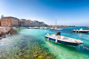 Several fishing boats at the Otranto harbour - coastal town in Puglia with turquoise sea
